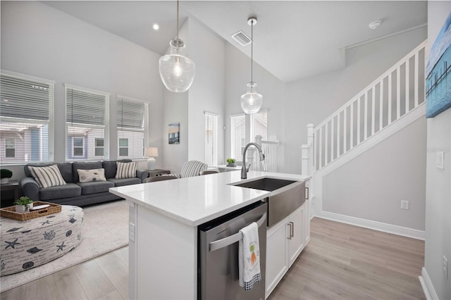 kitchen with white cabinetry, stainless steel dishwasher, a healthy amount of sunlight, and light hardwood / wood-style flooring