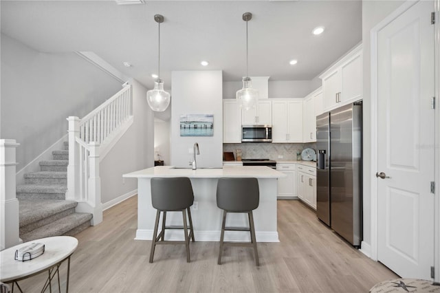 kitchen with white cabinets, light wood-type flooring, and appliances with stainless steel finishes