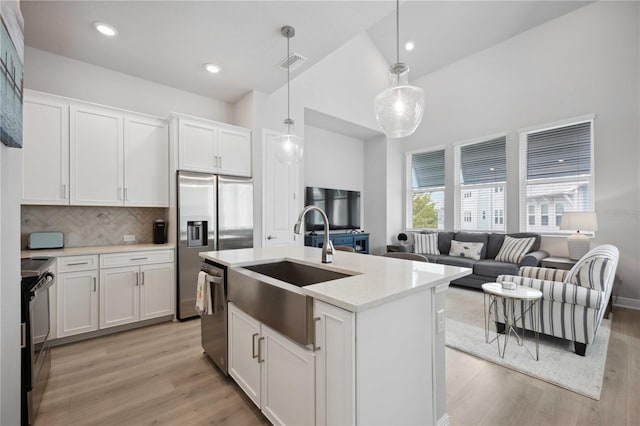 kitchen featuring white cabinets, appliances with stainless steel finishes, hanging light fixtures, and light hardwood / wood-style floors