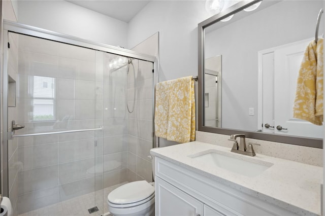 bathroom with a shower with shower door, vanity, and toilet