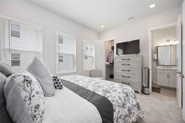 carpeted bedroom featuring ensuite bath, sink, a spacious closet, and a closet