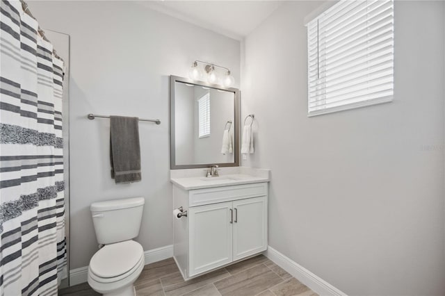 bathroom with vanity, curtained shower, a healthy amount of sunlight, and toilet