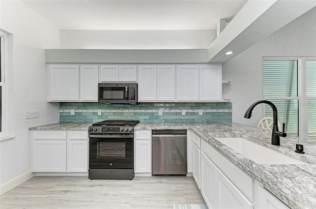 kitchen featuring sink, backsplash, white cabinetry, and appliances with stainless steel finishes