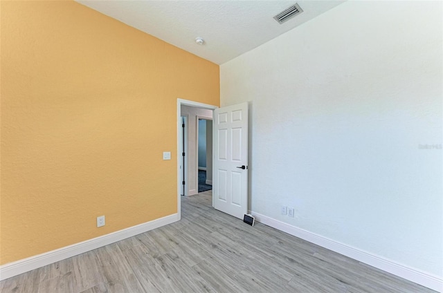 unfurnished room featuring light wood-type flooring and vaulted ceiling