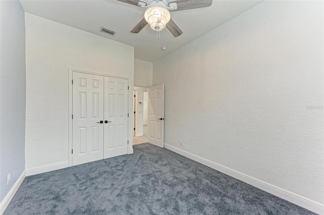 unfurnished bedroom with dark colored carpet, a closet, and ceiling fan