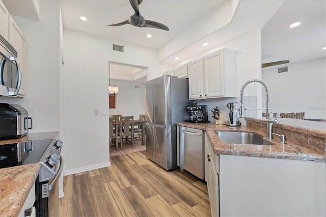 kitchen featuring light hardwood / wood-style floors, light stone counters, sink, white cabinetry, and appliances with stainless steel finishes