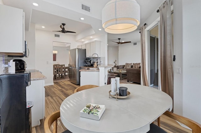 dining space with sink, ceiling fan, and light hardwood / wood-style flooring