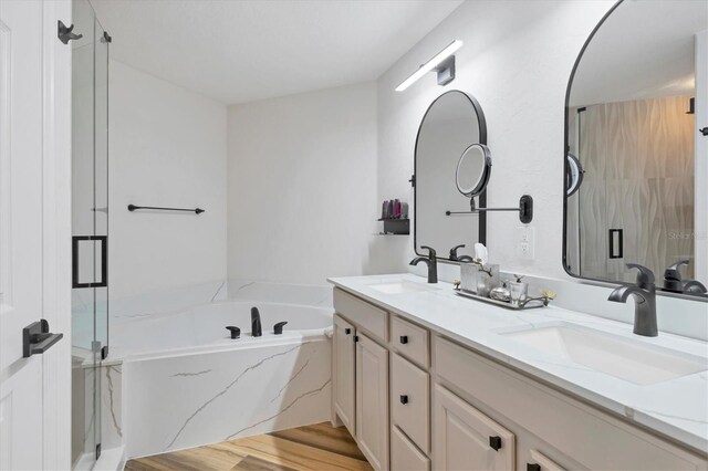 bathroom featuring hardwood / wood-style flooring, vanity, and shower with separate bathtub