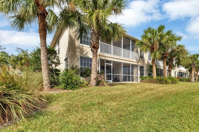 rear view of house featuring a sunroom and a yard