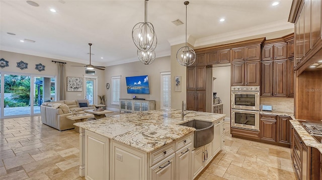 kitchen featuring stainless steel double oven, a large island, pendant lighting, sink, and ceiling fan with notable chandelier