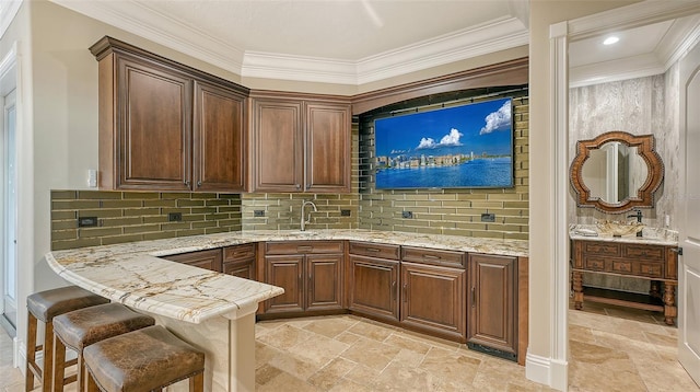 bar featuring sink, decorative backsplash, light stone counters, and ornamental molding