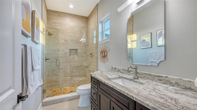 bathroom featuring toilet, vanity, tile patterned floors, and a shower with shower door