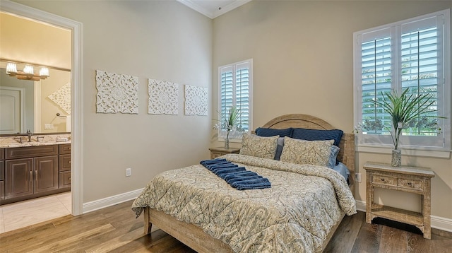 bedroom with ornamental molding, ensuite bath, wood-type flooring, and sink