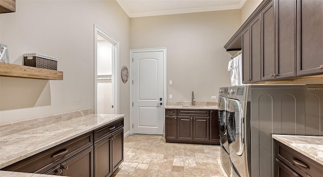 washroom with ornamental molding, washer and clothes dryer, cabinets, and sink