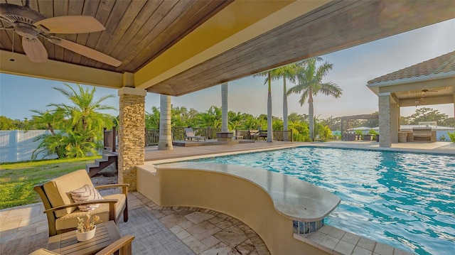 view of pool with exterior kitchen, ceiling fan, and a patio area