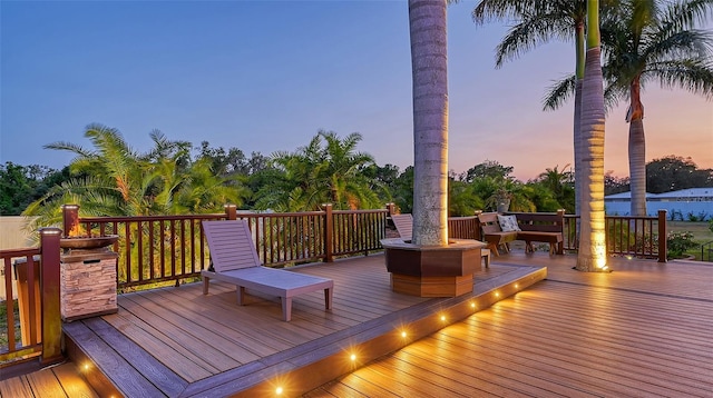 deck at dusk with a fire pit and a water view