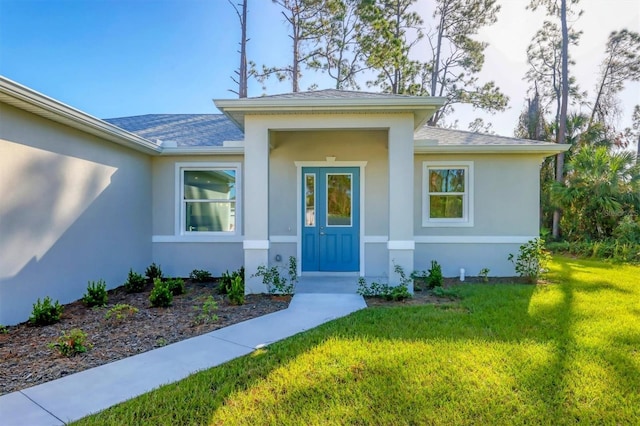 2814 Daphne Rd, North Port, FL 34288 - doorway to property featuring stucco siding, a lawn, and roof with shingles