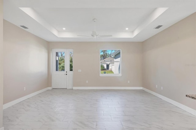 unfurnished room with ceiling fan and a tray ceiling