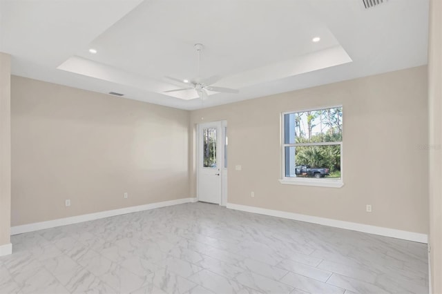 spare room with ceiling fan and a raised ceiling