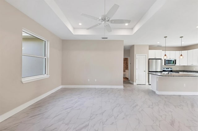 kitchen with ceiling fan, hanging light fixtures, stainless steel appliances, a raised ceiling, and white cabinets