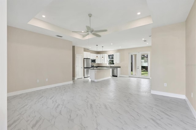 unfurnished living room with a raised ceiling and ceiling fan