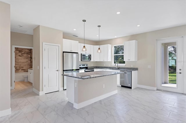 kitchen featuring dark stone counters, stainless steel appliances, pendant lighting, white cabinets, and a kitchen island