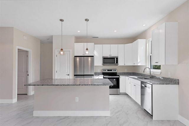 kitchen with appliances with stainless steel finishes, white cabinetry, a kitchen island, and pendant lighting