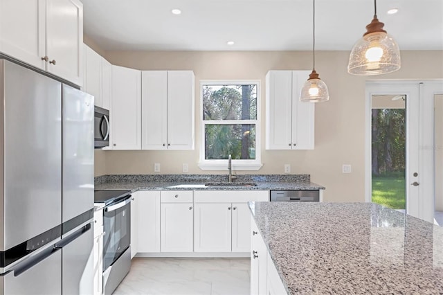 kitchen featuring light stone countertops, appliances with stainless steel finishes, sink, white cabinetry, and hanging light fixtures