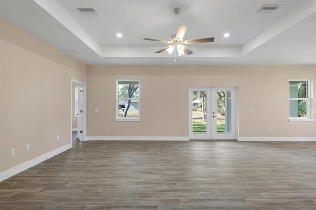 unfurnished room with a wealth of natural light, ceiling fan, and a tray ceiling