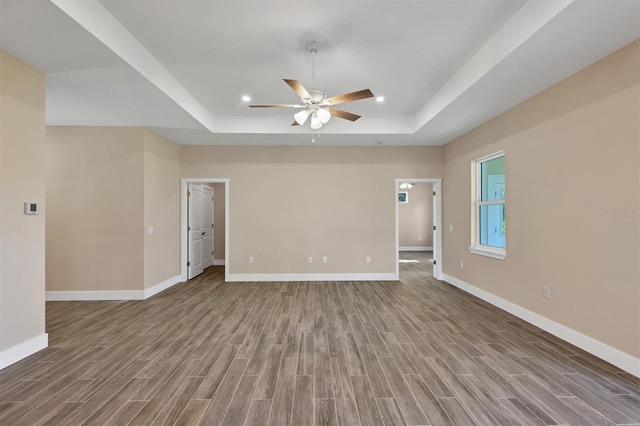 empty room featuring a tray ceiling, hardwood / wood-style floors, and ceiling fan