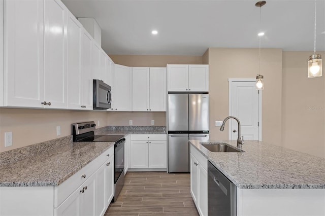 kitchen featuring white cabinetry, sink, appliances with stainless steel finishes, pendant lighting, and light wood-type flooring