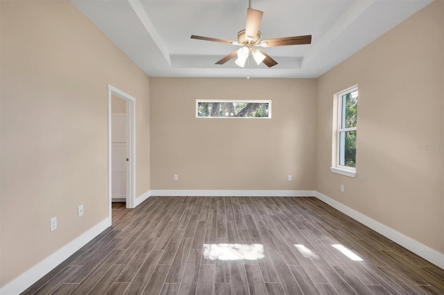 spare room featuring ceiling fan, dark hardwood / wood-style flooring, and a tray ceiling