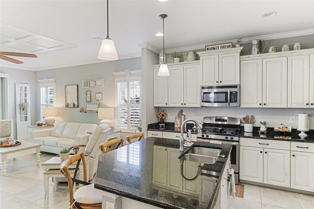 kitchen with an island with sink, plenty of natural light, white cabinets, and appliances with stainless steel finishes