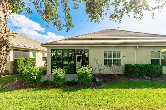 rear view of property with a lawn and a sunroom