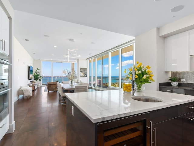 kitchen with expansive windows, beverage cooler, dark brown cabinetry, and plenty of natural light