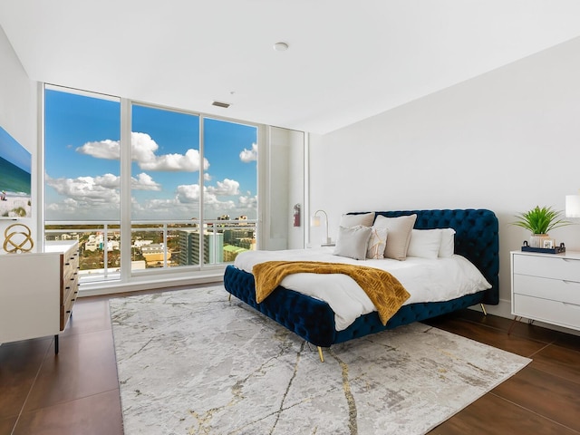 bedroom featuring expansive windows and dark hardwood / wood-style flooring