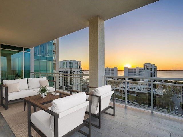 balcony at dusk with a water view and an outdoor living space