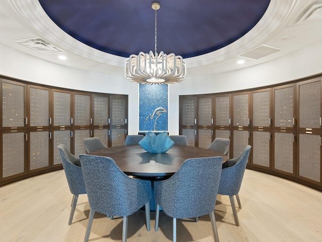 dining room with light wood-type flooring, a raised ceiling, and an inviting chandelier