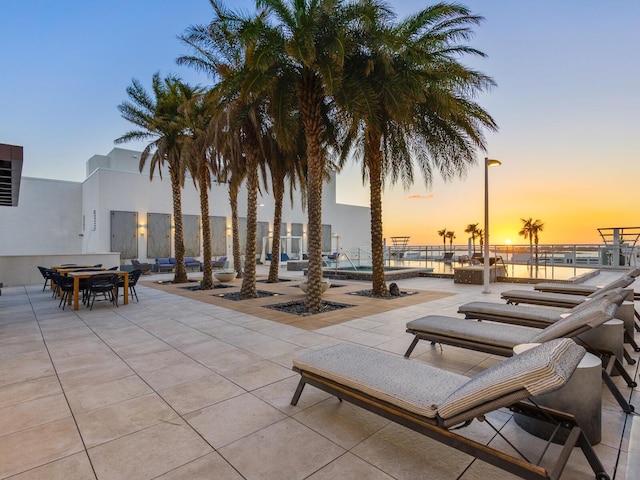 patio terrace at dusk with a water view and a community pool