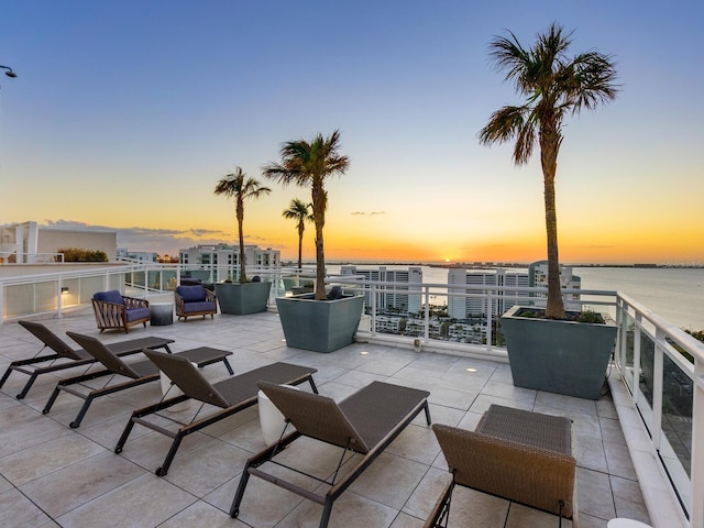 patio terrace at dusk with a water view and a balcony