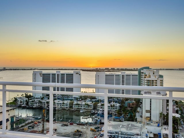 balcony at dusk featuring a water view