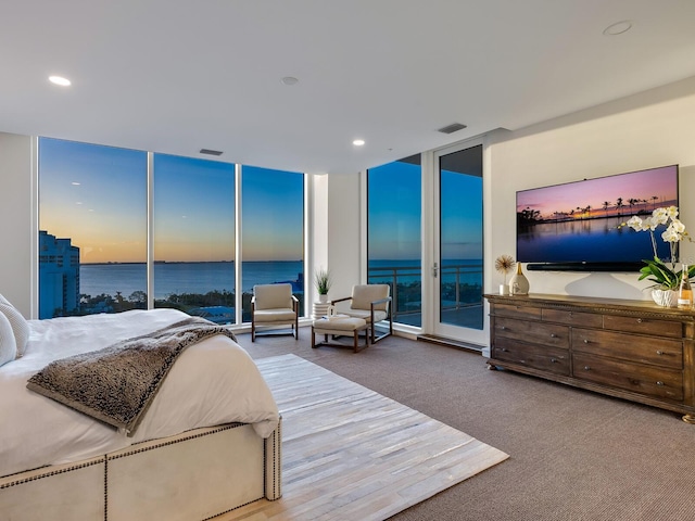 carpeted bedroom featuring a water view, floor to ceiling windows, and access to outside