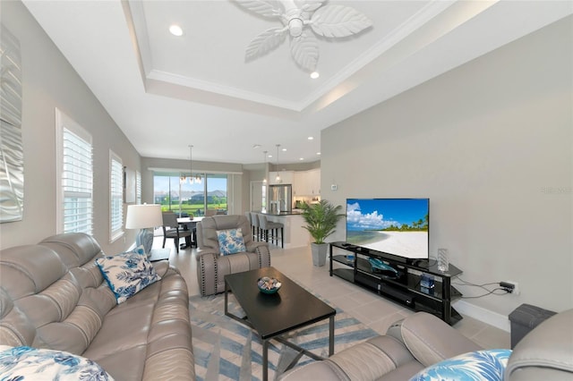 living room featuring ceiling fan, ornamental molding, and a tray ceiling