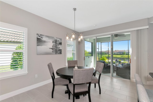 tiled dining space with ceiling fan with notable chandelier and a wealth of natural light