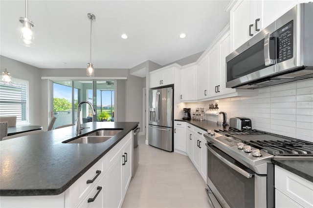 kitchen featuring sink, stainless steel appliances, decorative backsplash, pendant lighting, and a kitchen island with sink