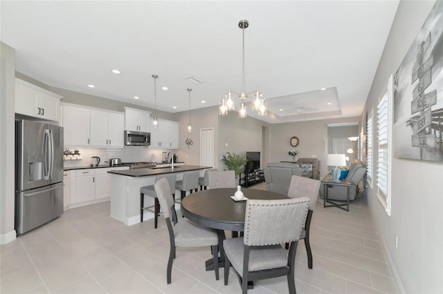 dining area featuring a raised ceiling, light tile patterned floors, and sink