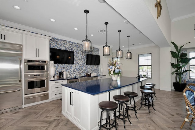 kitchen with ornamental molding, stainless steel appliances, light parquet floors, a center island, and white cabinetry