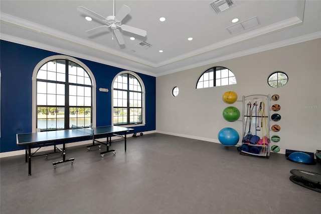 interior space with a tray ceiling, ceiling fan, a healthy amount of sunlight, and ornamental molding