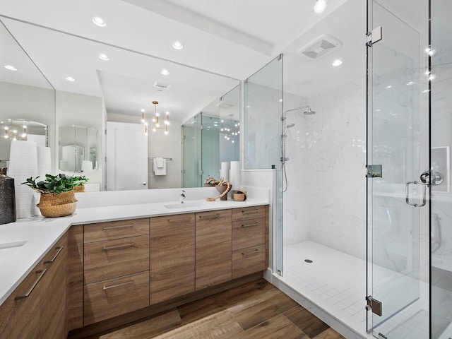 bathroom with hardwood / wood-style floors, walk in shower, a chandelier, and vanity