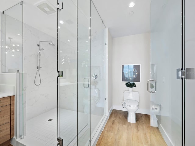 bathroom with hardwood / wood-style flooring, a shower with door, and toilet